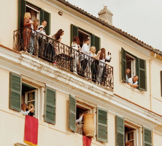Exterior of hotel with people standing on the balconies and celebrating.