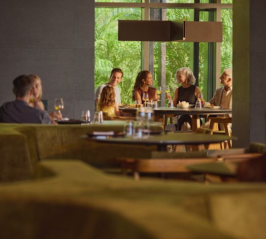 Rodina skládající se z dědečka, babičky, otce, matky a dcery, kteří si užívají jídlo v hotelové restauraci