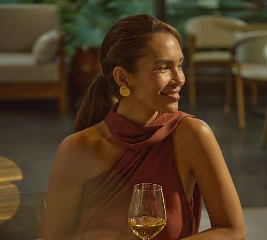 Portrait close up of woman in an elegant evening dress enjoying a glass of white wine in the Ceiba Club