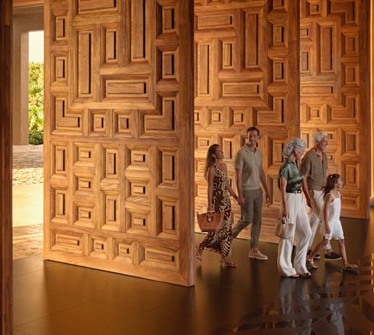 O familie formată din bunic, bunică, tată, mamă și fiică se plimbă prin holul hotelului