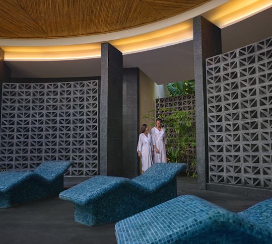 A woman and a man wearing bathrobes are walking through the spa