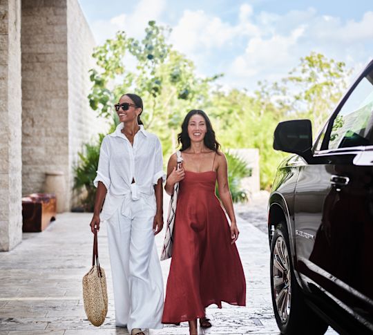 Două femei merg alături de o mașină mare neagră