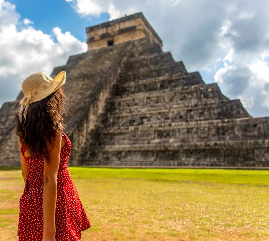 Frauen in einem roten Kleid mit Blick auf die Ruinen von Chichen Itza