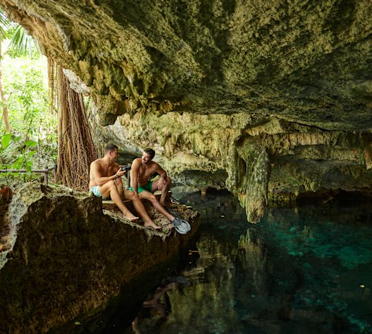 Men sitting on rocks near cave entrance