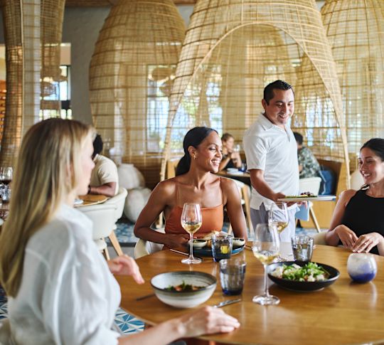 Gruppe von Personen, die im Restaurantbereich essen. Der Mitarbeiter betreut den Lebensmittelwechsel