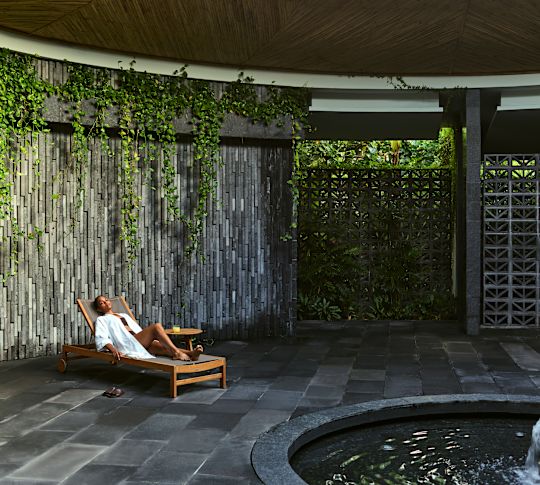 Woman relaxing on lounger, with water feature