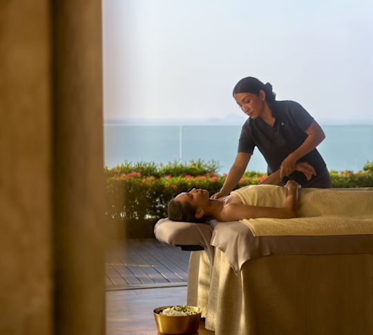 Woman receiving spa treatment from masseuse