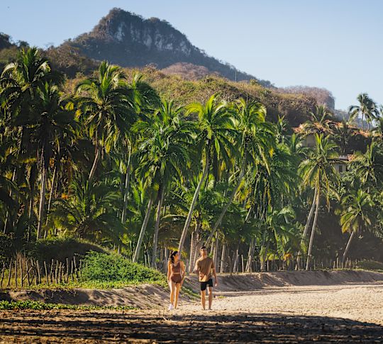 people walking along beach with view of mountains