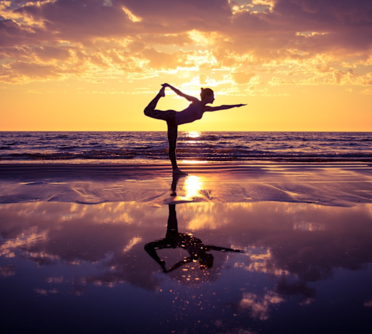 Femme pratiquant le yoga sur la plage au coucher du soleil