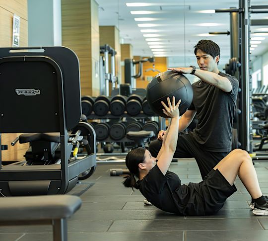 En kvinna med en tränare som tränar med styrkeutrustning på ett fitnesscenter