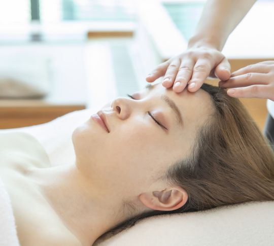 Woman laying face up with eyes closed undergoing spa treatment