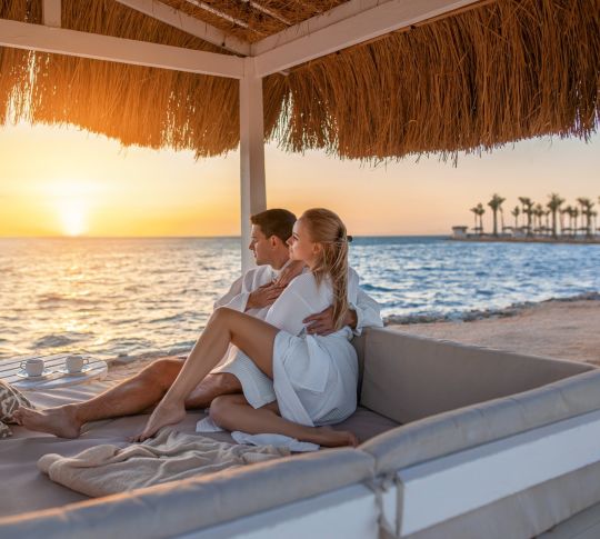 Couple in a cabana on the beach looking at sunset