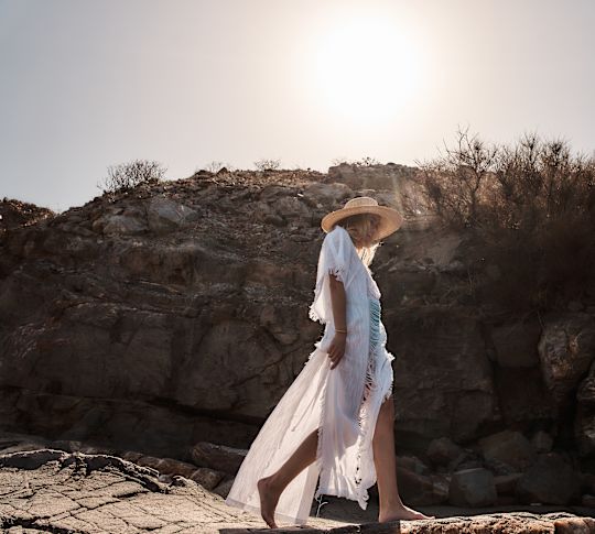 Woman Walking on Rocks Towards the Beach