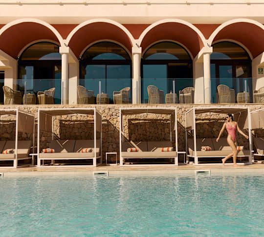 Außenpool mit Frau im Swimmingsuit, die an Liegestühlen vorbeiläuft