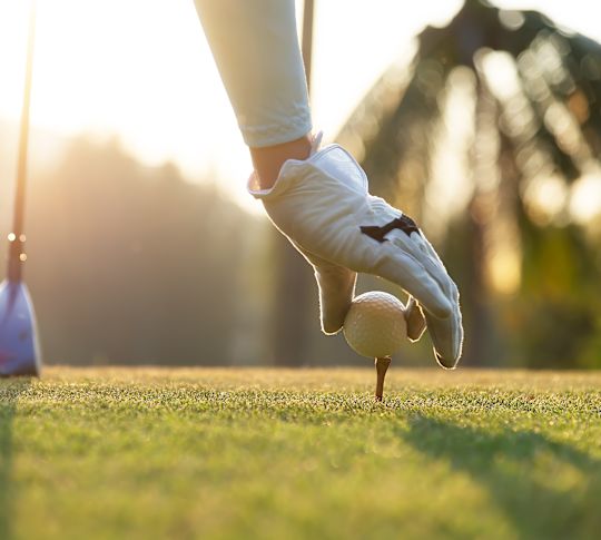 Ruka vkládající tričko do golfové zelené s klubem