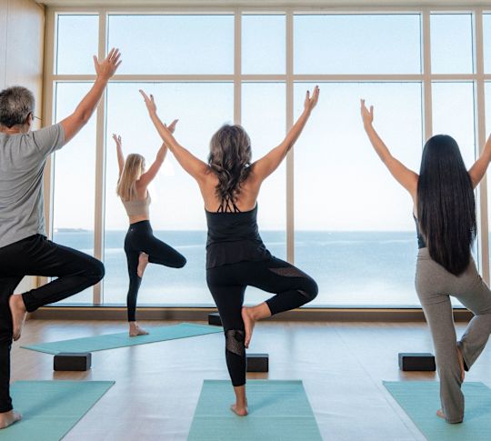 Oameni care practică yoga într-un Centru de fitness cu vedere spre mare