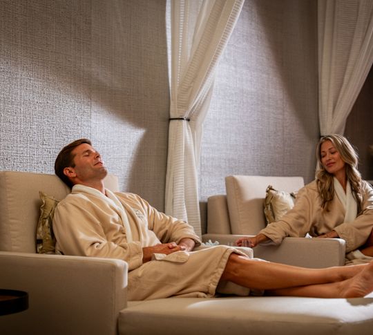 Bărbat și femeie stând pe șezlonguri din spa