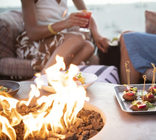 Ladies enjoying food and drinks by the Sun Deck fire pit