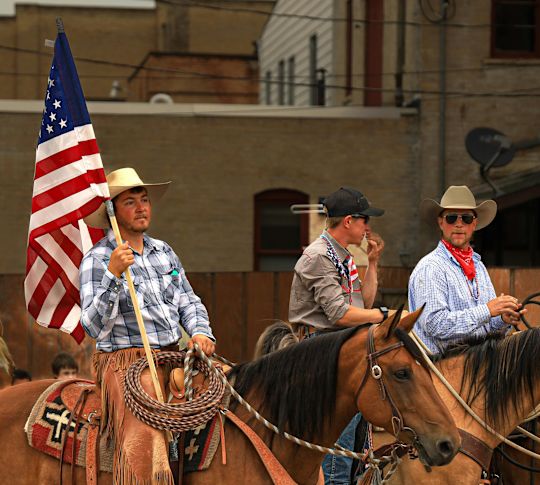 3 men on horses with an US flag at a parade or event taking place in Conroe, Texas