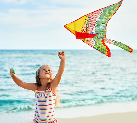 Girl Flying a Colorful Kite at the Beach