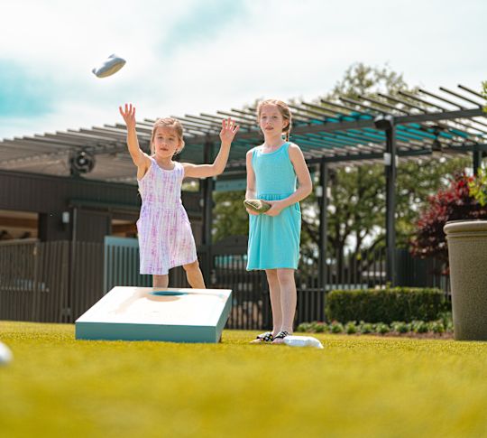 kids playing baggo / cornhole in the courtyard by Jade Waters, water park