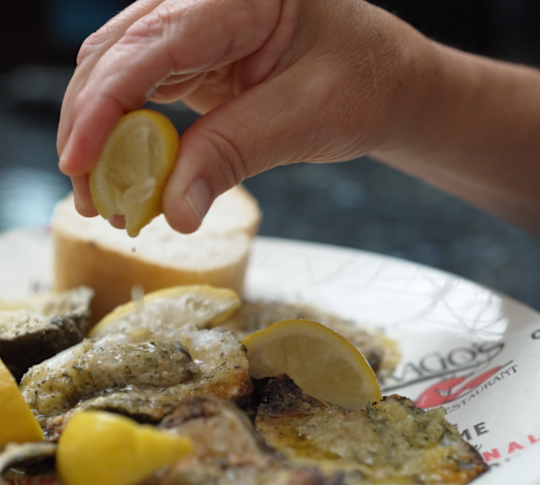 a Woman Adding Lemon Juice to a Plate with Oysters