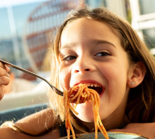 Fată mâncând spaghete într-un restaurant