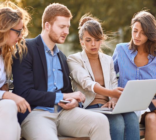 a Group of People Having a Meeting Using a Laptop in the Garden