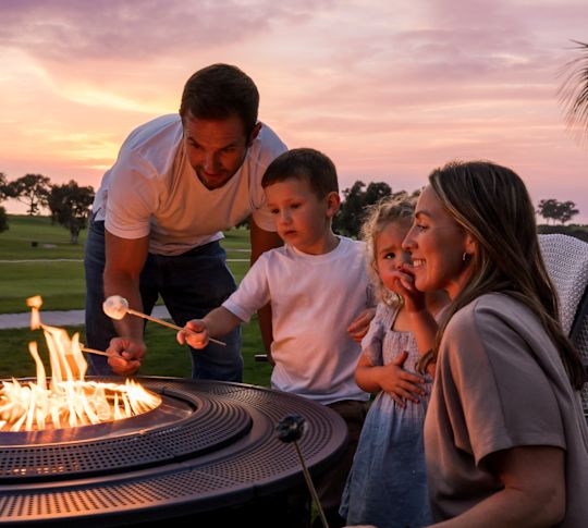 a family enjoying smores at sunset on the courtyard  firepit