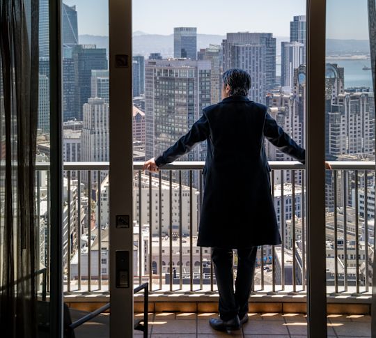 A Man Enjoying the City View from His Guest Room Balcony