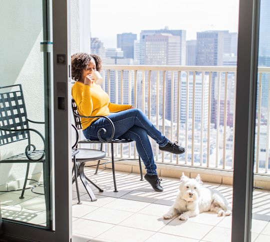 A Woman with White Dog is Having Coffee in a Guest Room Balcony with City View