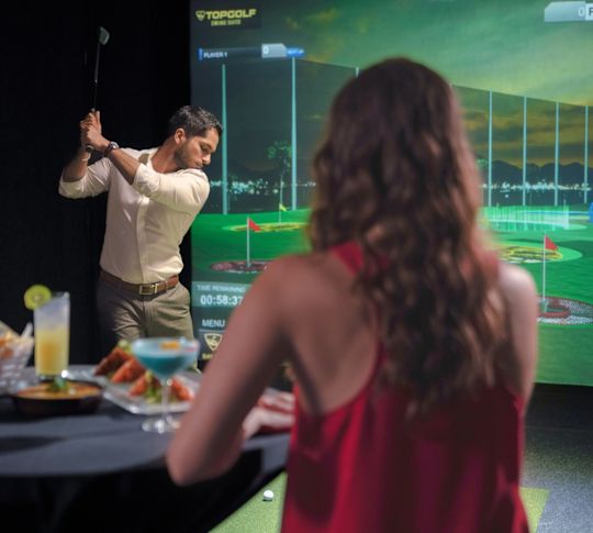 Peopl playing in the TopGolf suite