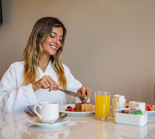 Woman eating room service breakfast in robe
