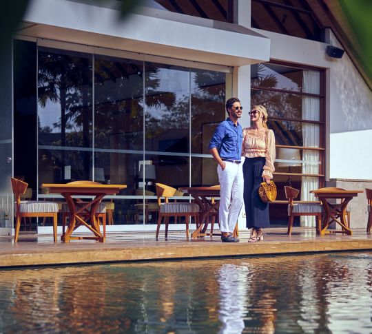 Couple standing on deck of pool villa