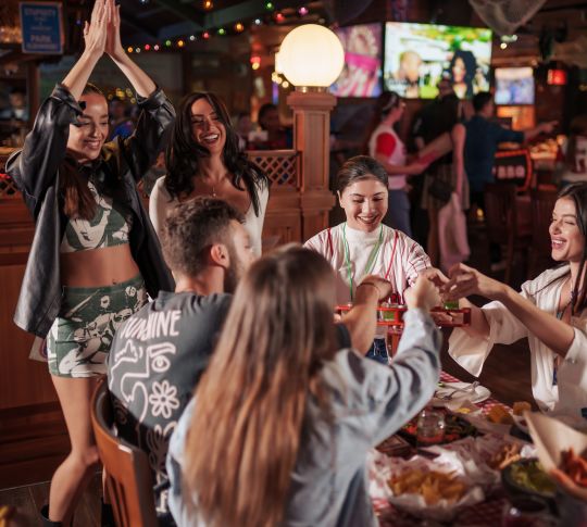Group of young adults in restaurant, with drinks and snacks