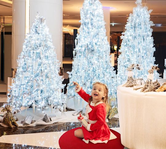 Girl with white Christmas trees behind her