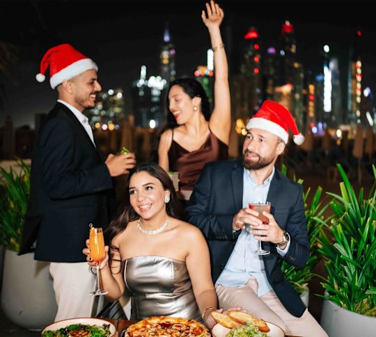 Jones the Grocer people in Santa hats on terrace with city behind them