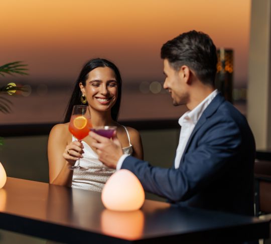 couple toasting drinks at outdoor bar at dusk