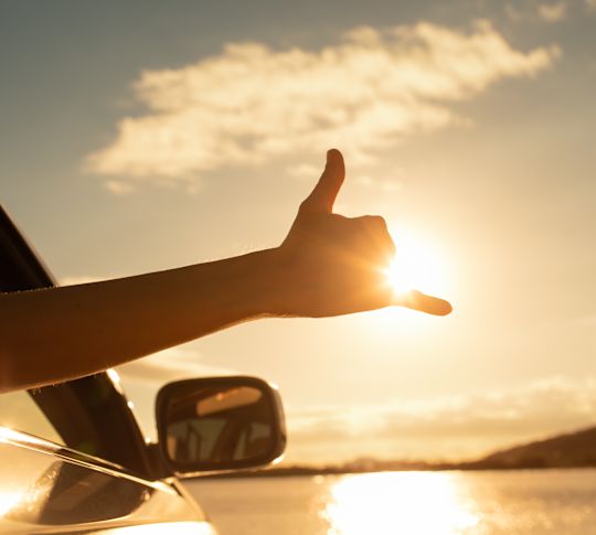 Person holding arm outside of car with thumbs up