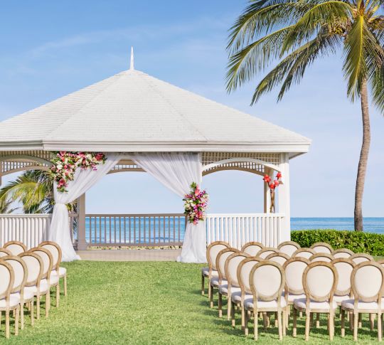 Outdoor venue set up for a wedding, chairs face a gazebo