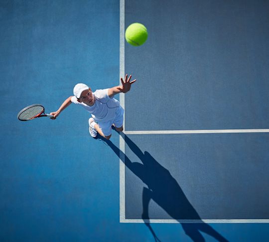 テニスコートでサービスを提供する男性