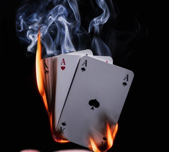 magician's hand with playing cards on fire