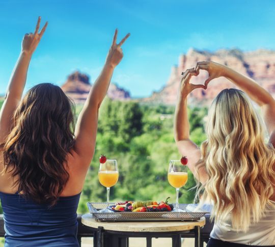 women on balcony with drinks and fruit