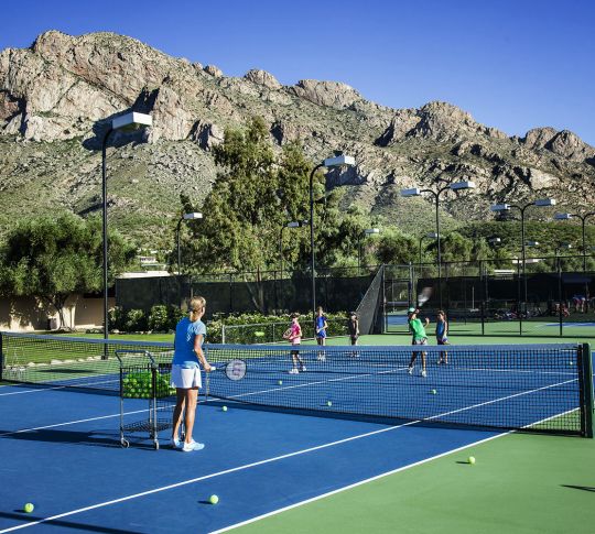 Люди играют в теннис с горами на заднем плане