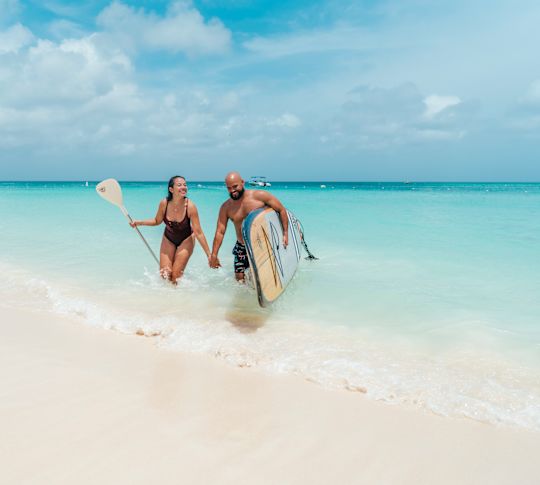 couple with paddle board on beach
