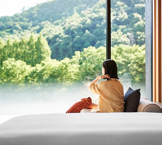 woman sitting in guestroom looking out window