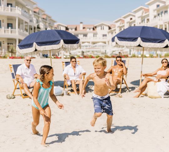 children running with parents in background on beach