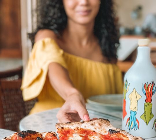 woman taking slice of pizza from dish
