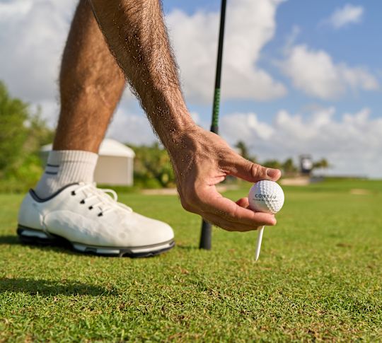 Bărbat plasând o minge de golf pe un tricou