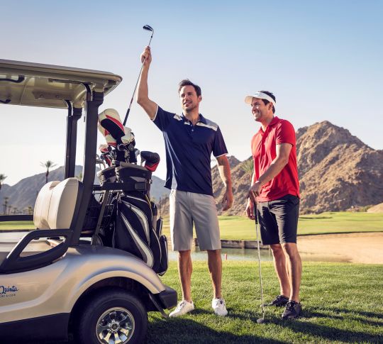 Two golfers getting clubs out of golf cart